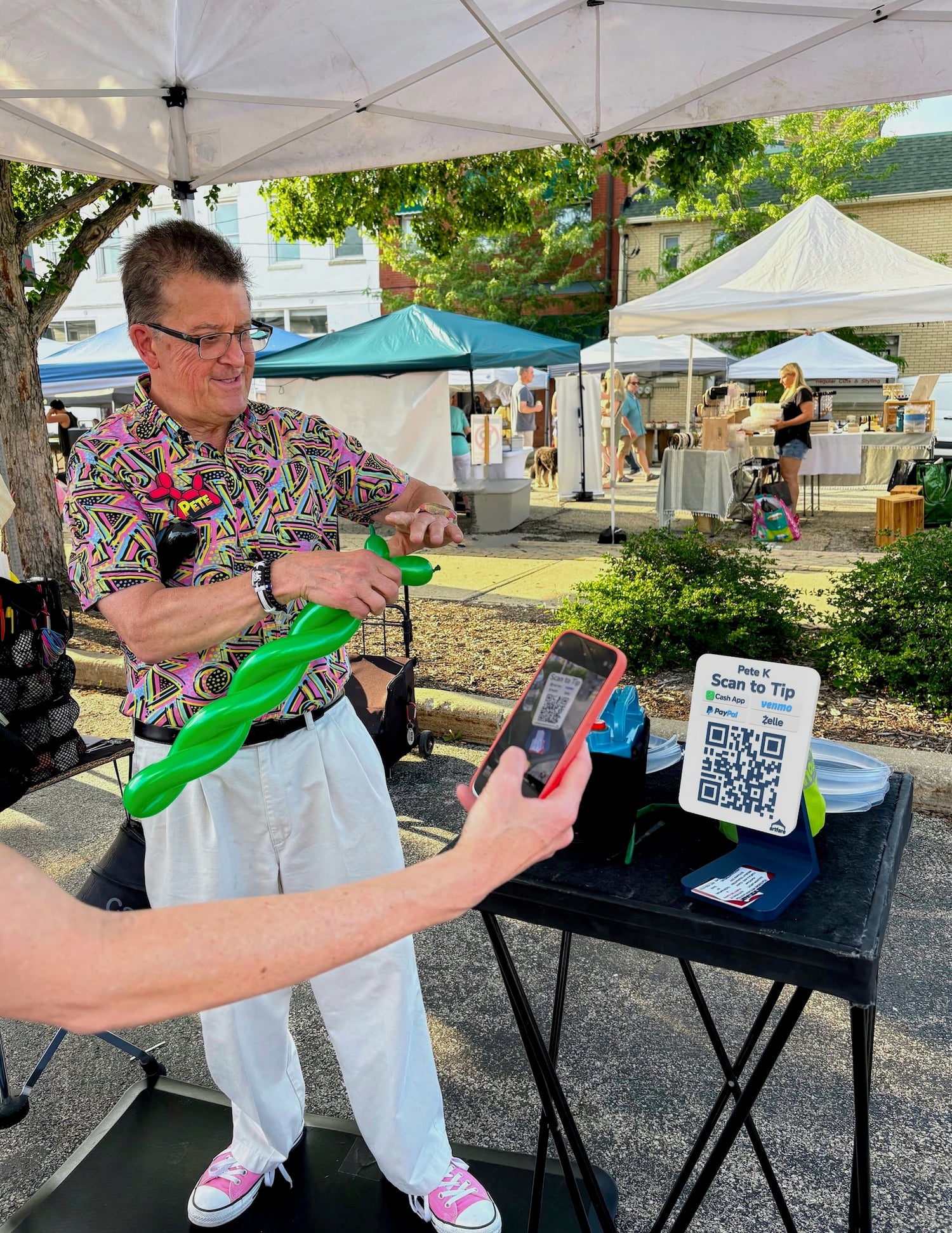 Balloon twister performer using Artfare QR payment sign at event for Scan to Tip