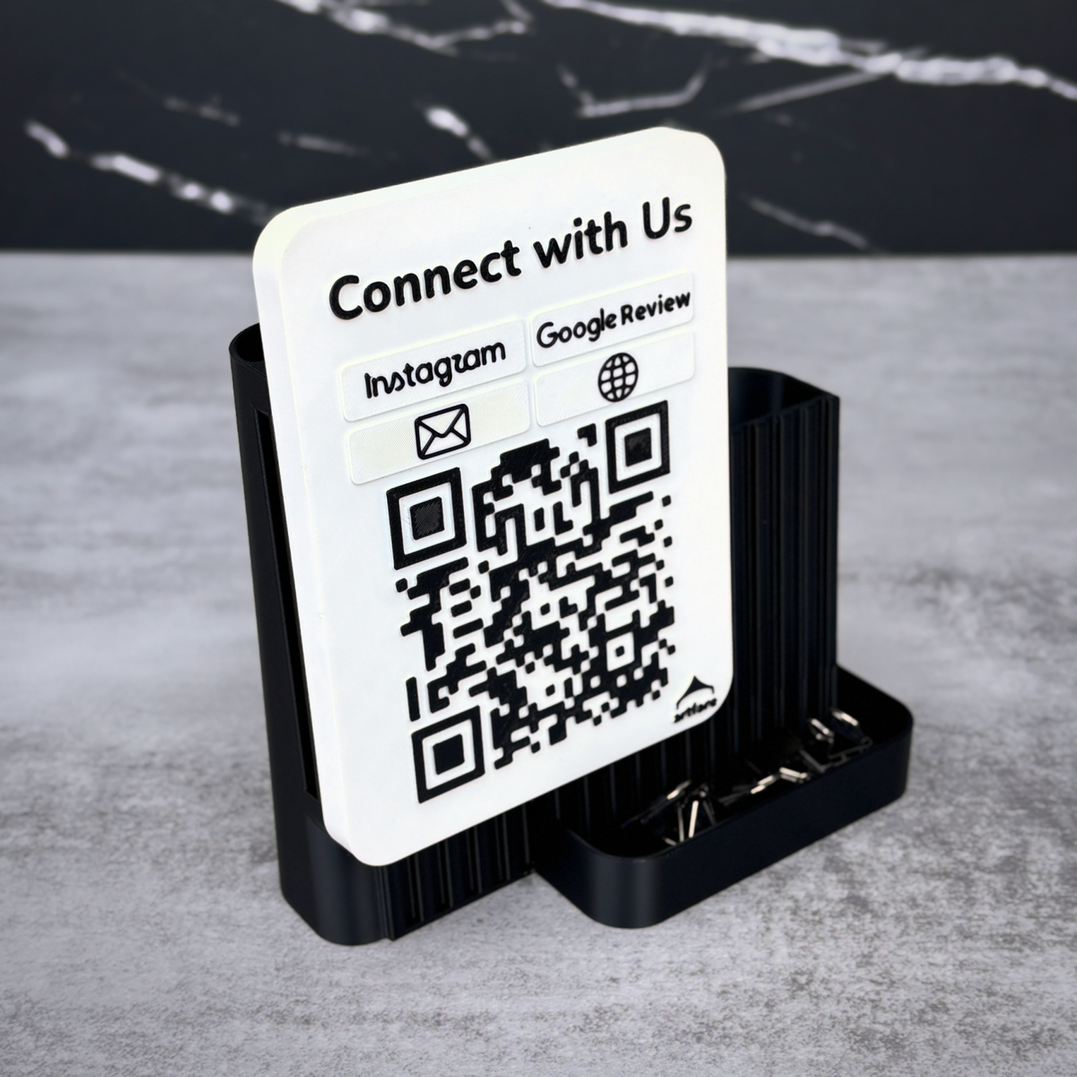 Black Shopkeeper Connect with Us sign on marble with paper clips in the front tray